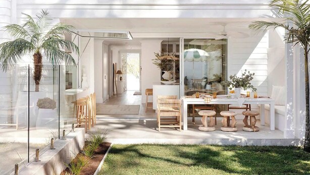 Een modern huis met een eethoek, terras en een groot raam.