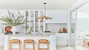 Een moderne keuken met een centraal eiland, witte kasten en een hangende lamp.