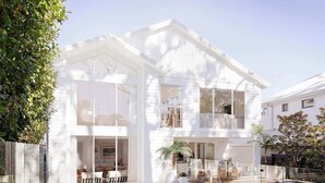 Een huis met twee verdiepingen, grote ramen, een zwembad en tuinmeubilair.