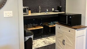 Une cuisine compacte avec un crédence noire à motifs hexagonaux, un four à micro-ondes et un évier.