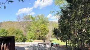 Un terrain de camping doté d’une terrasse en bois, de tables de pique-nique abritées et d’un mur en pierre.