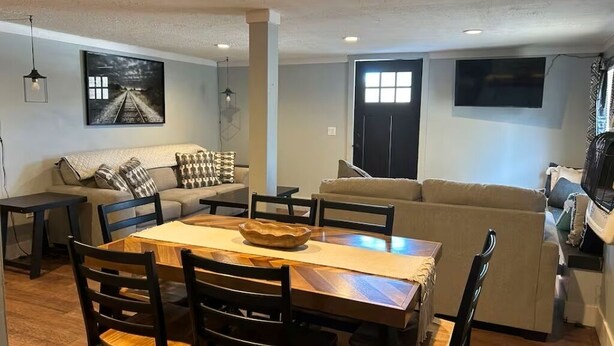 Un coin repas avec une table et des chaises en bois, un canapé et un tableau accroché au mur.