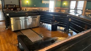 A kitchen with a central island, wooden flooring, and a view of the dining area. - Narrowsburg Inn Vacations (Narrowsburg)