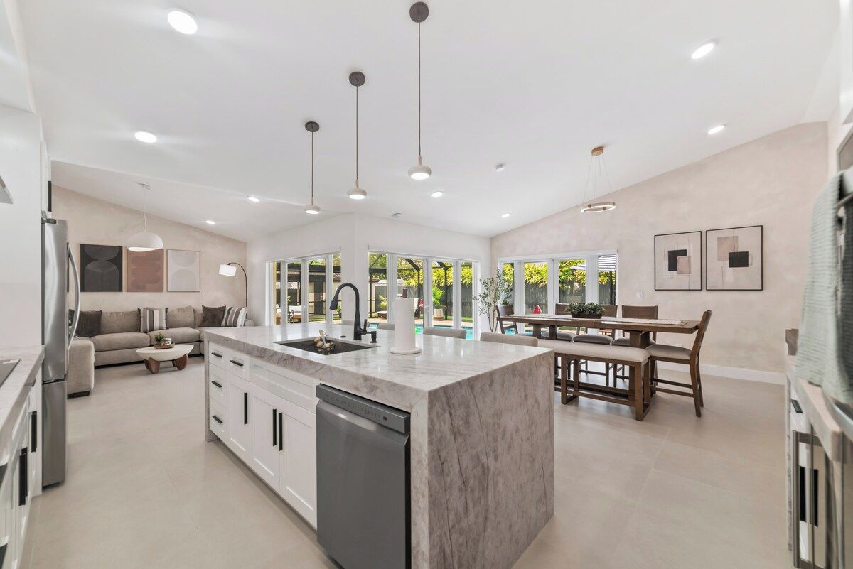 A spacious kitchen with a central island, a dining area with a table and chairs, and a built-in dishwasher.