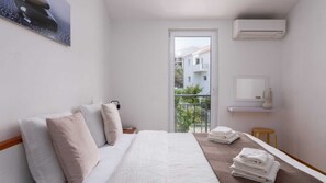 A hotel room with a bed, a small table with towels, a balcony, and an air conditioning unit. - Charming apartment Mi Mara (Okrug Gornj)