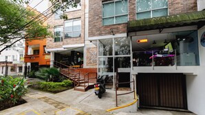 Un edificio con escaparate de vidrio, una motocicleta estacionada afuera y una escalera que lleva a la entrada.