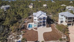 A multi-story house with a pool, surrounded by dense trees and a clear view of the ocean. - Rising Sun Pool Elevator  Pet Beach Access (Eastpoint)