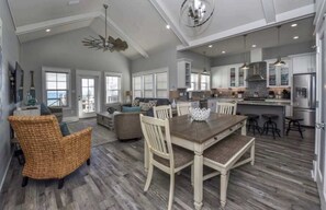 A spacious living area with a dining table, wicker chair, and a view of the ocean. - Rising Sun Pool Elevator  Pet Beach Access (Eastpoint)