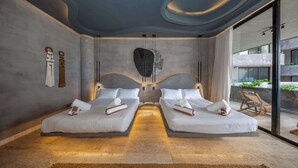Une chambre d’hôtel moderne avec deux lits, une grande sculpture en pierre et une vue sur le balcon extérieur.