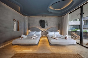 A modern hotel room with two beds, a large stone sculpture, and a view of the outside balcony. - Oceanfront luxury 3BR in Tankah w/ Private Beach (Tulum)