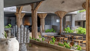 Un espace extérieur aménagé avec des tables et des chaises, entouré de plantes et de colonnes décoratives.