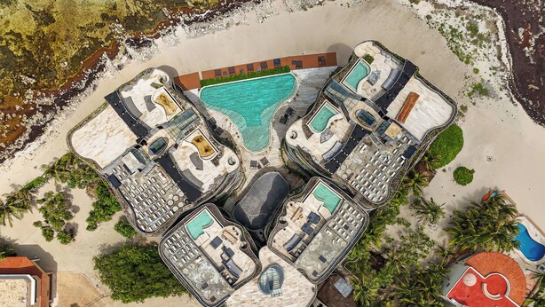 Vue aérienne d’un complexe hôtelier doté de plusieurs piscines, d’une plage et d’un parking.