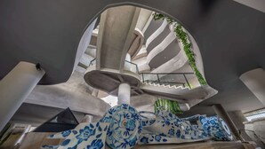 Un intérieur architectural moderne, agrémenté d’un escalier en colimaçon, d’un motif floral décoratif bleu et blanc, et d’une enseigne portant l’inscription « maiim ».