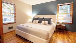 Un dormitorio con una cama grande, dos mesitas de noche y una ventana con persianas.