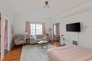 A modern bedroom with a bed, a sofa, a TV, and a small table.