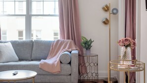 A living room with a sofa, a round coffee table, a floor lamp, and a side table with a vase of flowers. - Spacious Studio Steps to 23rd & Trader Joe's + Parking Included (Portland)