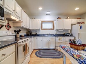 A kitchen with white cabinets, a stove, a sink, and a window.