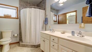 Une salle de bain comprenant une douche, des toilettes, un meuble-lavabo avec un évier et un miroir.