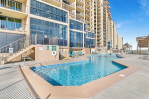 A hotel with a swimming pool, multiple balconies, and a lifeguard stand. - 3-bedroom Ocean front condo in Ocean Beach. Skip the elevator, keep the view! (Orange Beach)