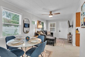 A dining area with a round table, blue chairs, and a ceiling fan. - Lakeland Group Retreat | Sleeps 18 Across 3 Private Units | Walk to Lakes & Florida Southern (Lakeland)
