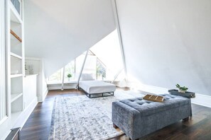 A high-ceilinged attic bedroom with a bed, a cushioned bench, a rug, and a potted plant. - Lakeland Group Retreat | Sleeps 18 Across 3 Private Units | Walk to Lakes & Florida Southern (Lakeland)
