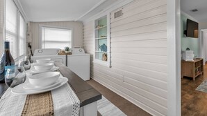 Una cocina con una isla central, lavadora y una estantería con motivos marinos.