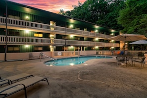 A multi-story motel with a pool area, outdoor seating, and a sunset view. - Cozy w/King Bed and Game Room! 5 Min to Parkway (Gatlinburg)