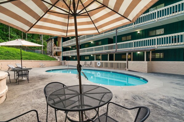 A pool area with a covered seating area and a two-story building in the background. - Cozy w/King Bed and Game Room! 5 Min to Parkway (Gatlinburg)