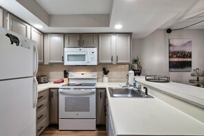 A modern kitchen with white cabinetry, a built-in microwave, a stainless steel sink, and a stove. - Cozy w/King Bed and Game Room! 5 Min to Parkway (Gatlinburg)