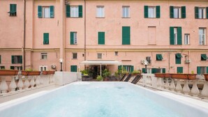 Une piscine sur le toit offrant une vue sur un bâtiment rose aux volets verts.