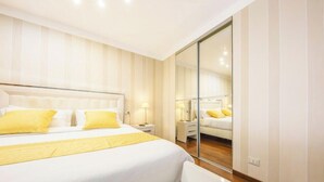 Une chambre à coucher avec un grand lit, des tables de chevet, un miroir et une porte coulissante.