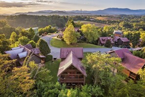 Ein Blockhotel im Chalet-Stil mit einem zentralen Gebäude, umgeben von Bäumen, einer kurvenreichen Straße und einer Bergkulisse.