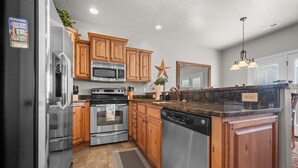 A kitchen with wooden cabinets, stainless steel appliances, a granite countertop, and a star decoration on the wall. - Aspen Tree Chalet |Snowbasin|By Pineview Reservoir (Mountain Green)
