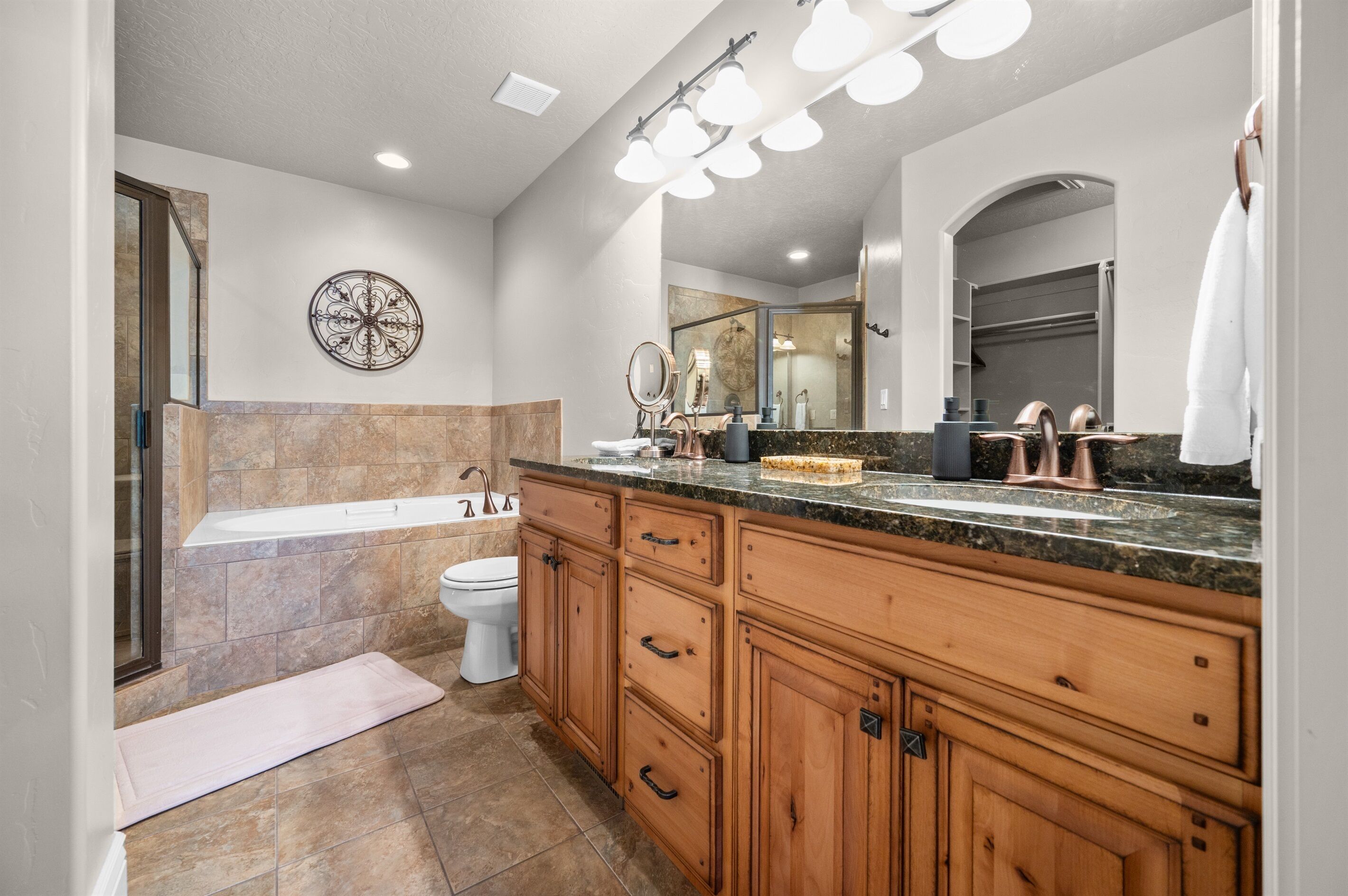 A bathroom with a bathtub, toilet, vanity with a mirror, and a towel rack.