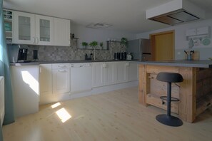 Eine moderne Küche mit weißen Schränken, einer Kaffeemaschine und einem Barhocker.