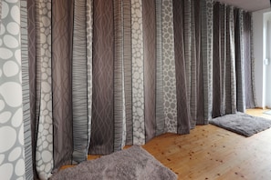 Ein Zimmer mit Holzboden, grauen Vorhängen mit verschiedenen Mustern und einem grauen Teppich.