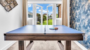 Et ping pong-bord med udsigt til en have gennem åbne franske døre.