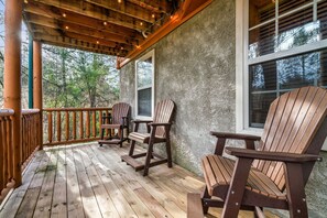 A wooden deck with Adirondack chairs and a rustic stone wall. - Hot Tub Hideaway! 5 Min to Parkway | Cozy n Quiet! (Pigeon Forge)