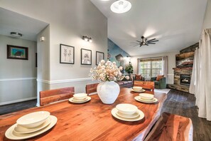 Un coin repas avec une table en bois dressée pour quatre personnes, un vase de fleurs et, au mur, des reproductions encadrées de panneaux de signalisation.