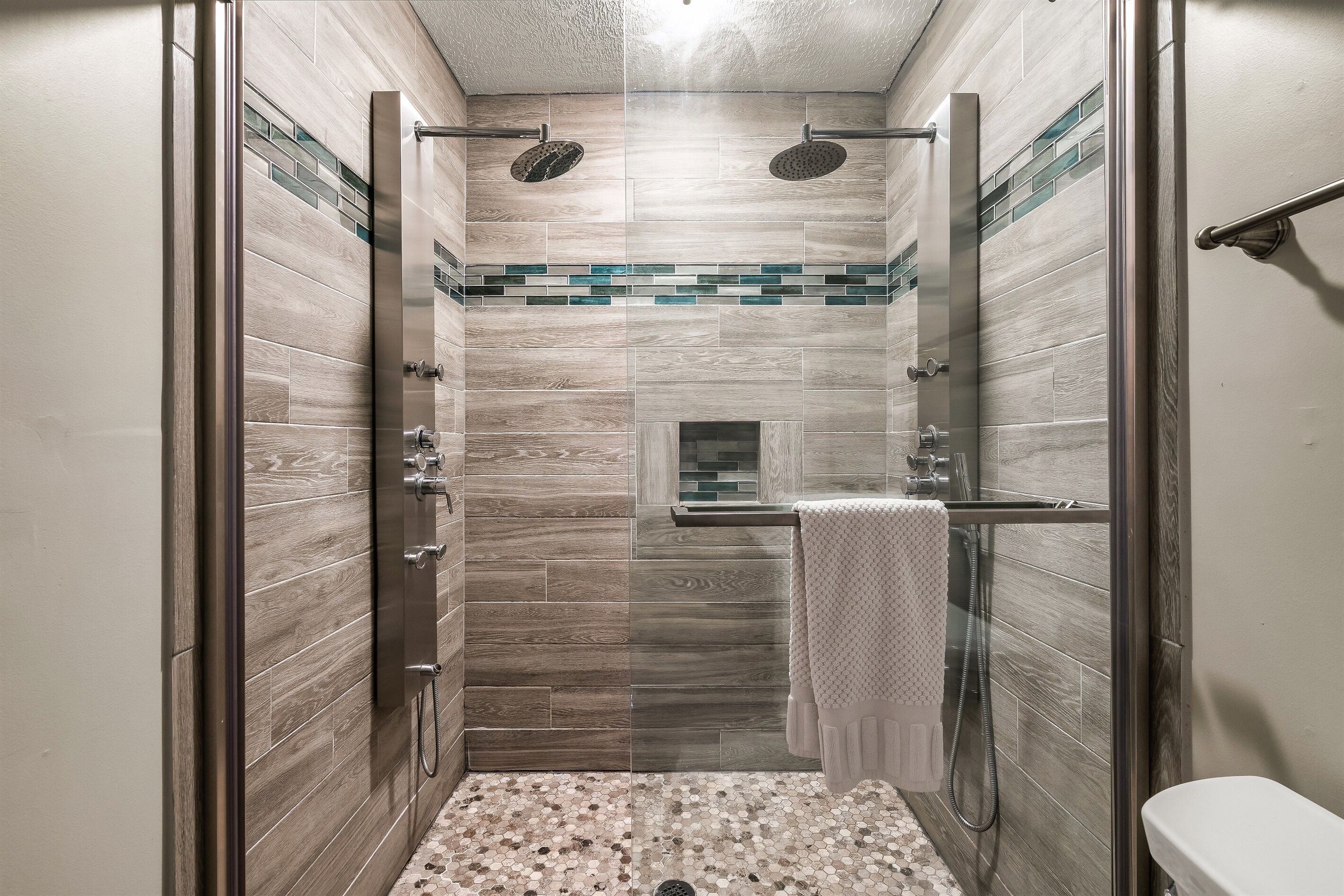A walk-in shower with a glass door, a tiled shower floor, and a towel rack.