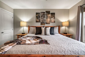 A bedroom with a large bed, two bedside lamps, a headboard, and a wall-mounted artwork. - Hot Tub Hideaway! 5 Min to Parkway | Cozy n Quiet! (Pigeon Forge)