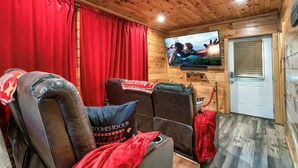 Ein gemütliches Zimmer mit Ledersessel, Wandfernseher und einer Tür mit Fenster.