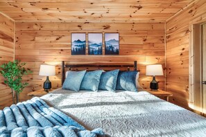 A wooden-paneled room with a bed, two nightstands, and a wall-mounted painting. - Hot Tub Hideaway! 5 Min to Parkway | Cozy n Quiet! (Pigeon Forge)