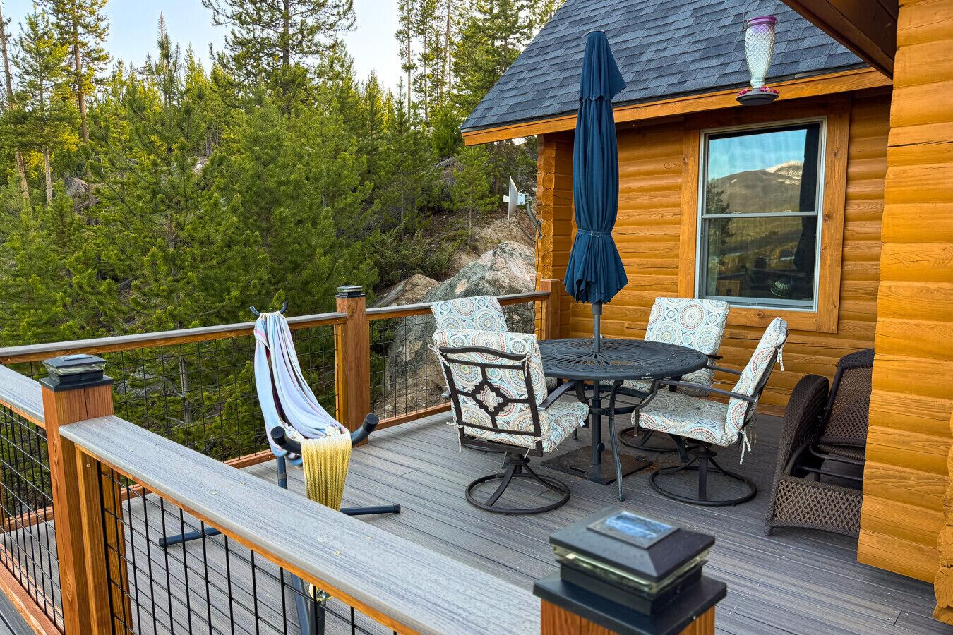 A wooden deck with outdoor furniture, a hammock, and a table with chairs.