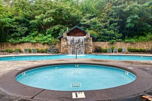 Ein Pool mit Wasserfall, umgeben von Steinmauern und üppiger Bepflanzung.