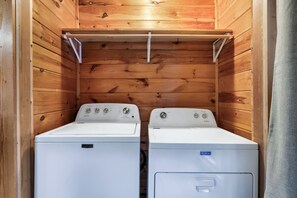 A laundry room with two Maytag washers and dryers, wooden walls, and a metal shelf above the dryers. - Falcon's Rest | 5 Min to Gatlinburg | Sleeps 18 (Gatlinburg)