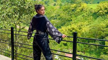 A person standing on a balcony with a view of a lush green landscape.