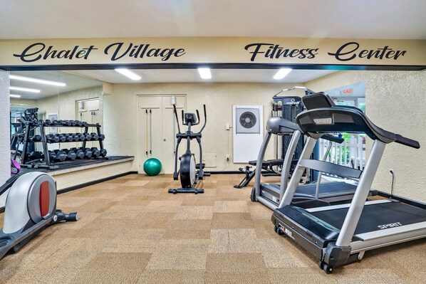 Ein Fitnessstudio mit Laufbändern, einem Hometrainer und Kurzhanteln.
