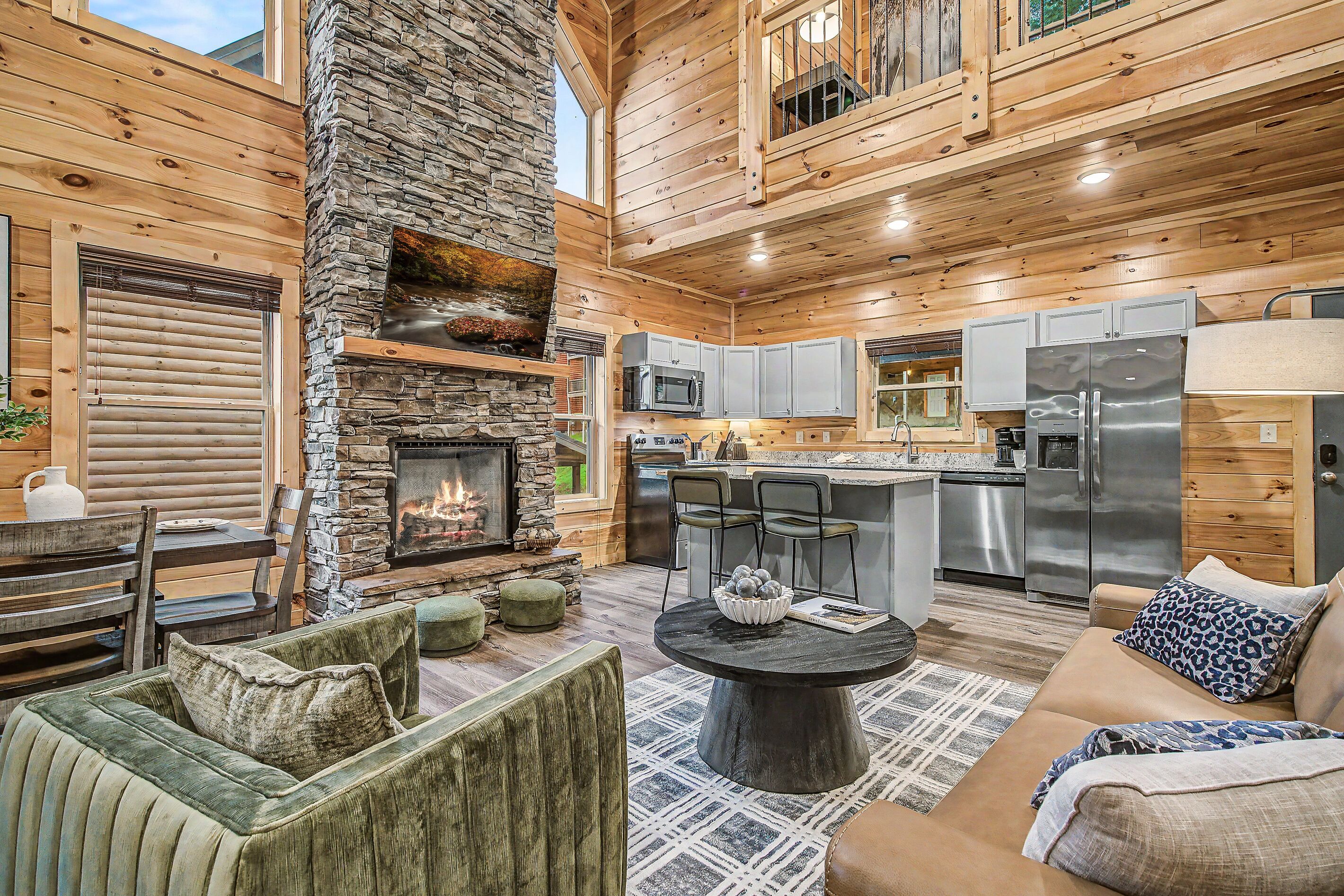 L’intérieur d’une cabane en rondins, avec une cheminée en pierre, des meubles en bois et un coin cuisine.