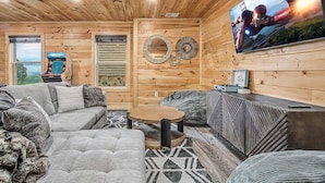 A cozy living room with a sofa, a coffee table, and a television mounted on the wall. - The Brookshire! Premium View | Hot Tub | Top 10% (Sevierville)
